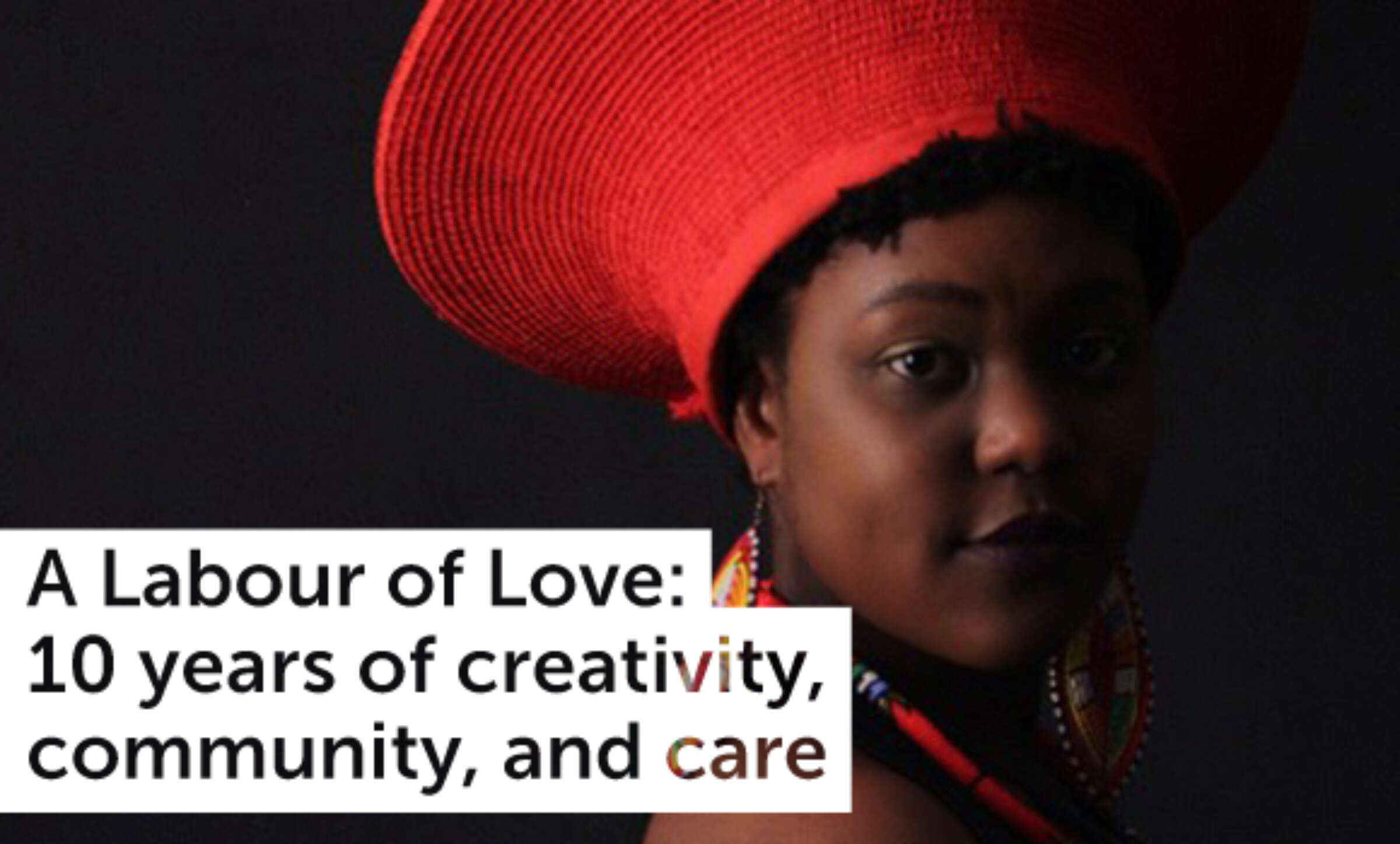 A person wearing a large, red hat and colorful accessories is seen against a dark background. The text on the left reads, "A Labour of Love: 10 years of creativity, community, and care.