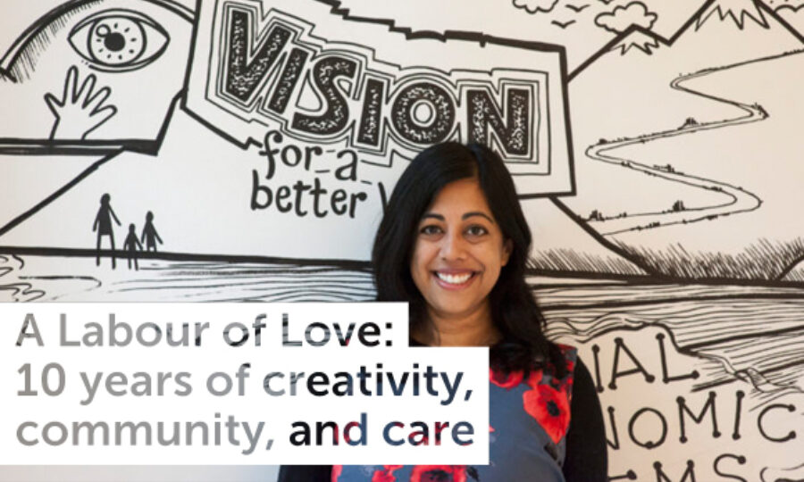 A woman with long dark hair is smiling in front of a black and white mural with the words "VISION for a better...". The text on the image reads, "A Labour of Love: 10 years of creativity, community, and care".