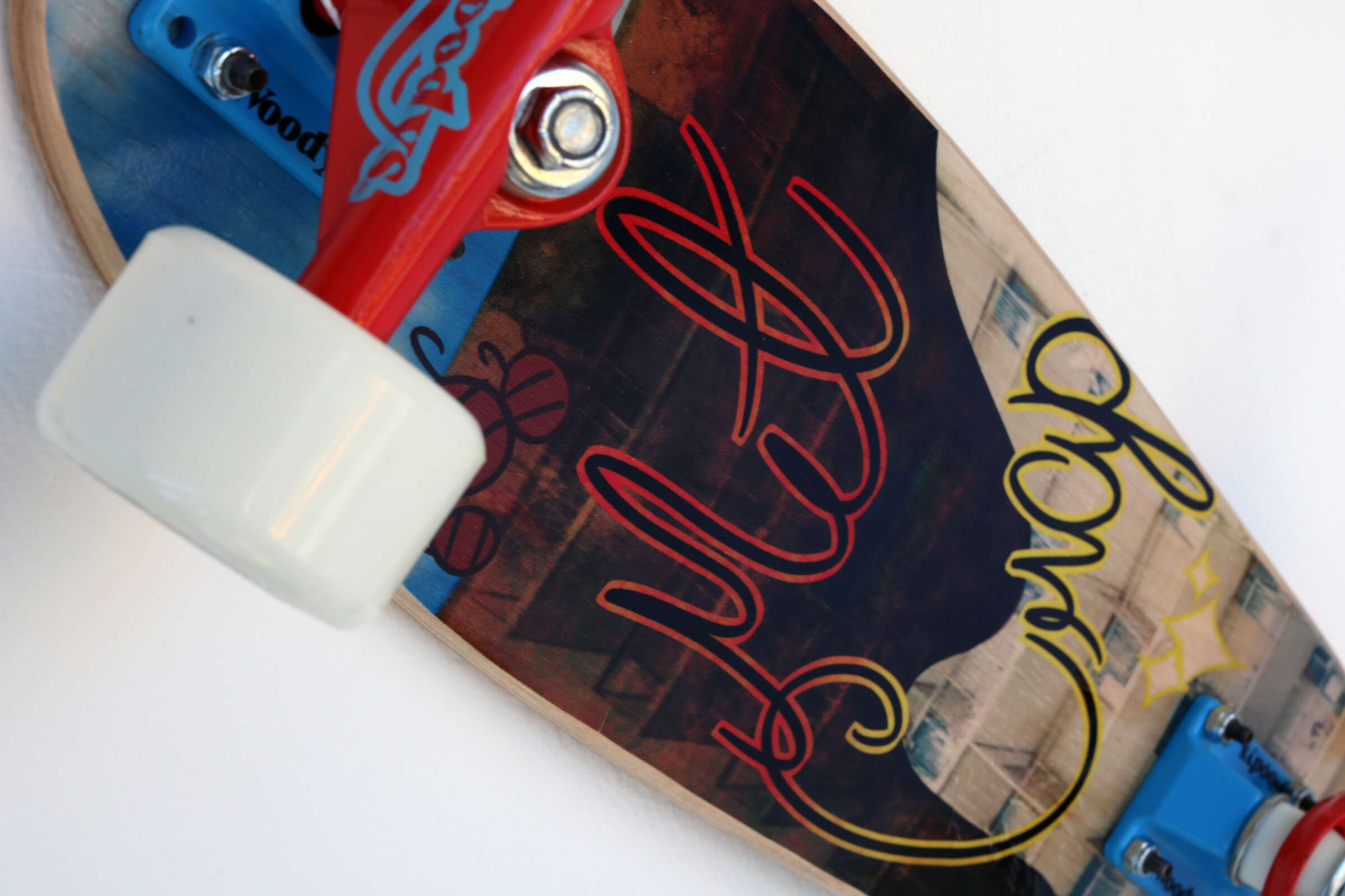 Close-up of a skateboard deck showcasing intricate artwork. The design includes abstract shapes and vibrant colors with the word "Globe" prominently featured. The truck is red with a white wheel, mounted to the wooden deck.