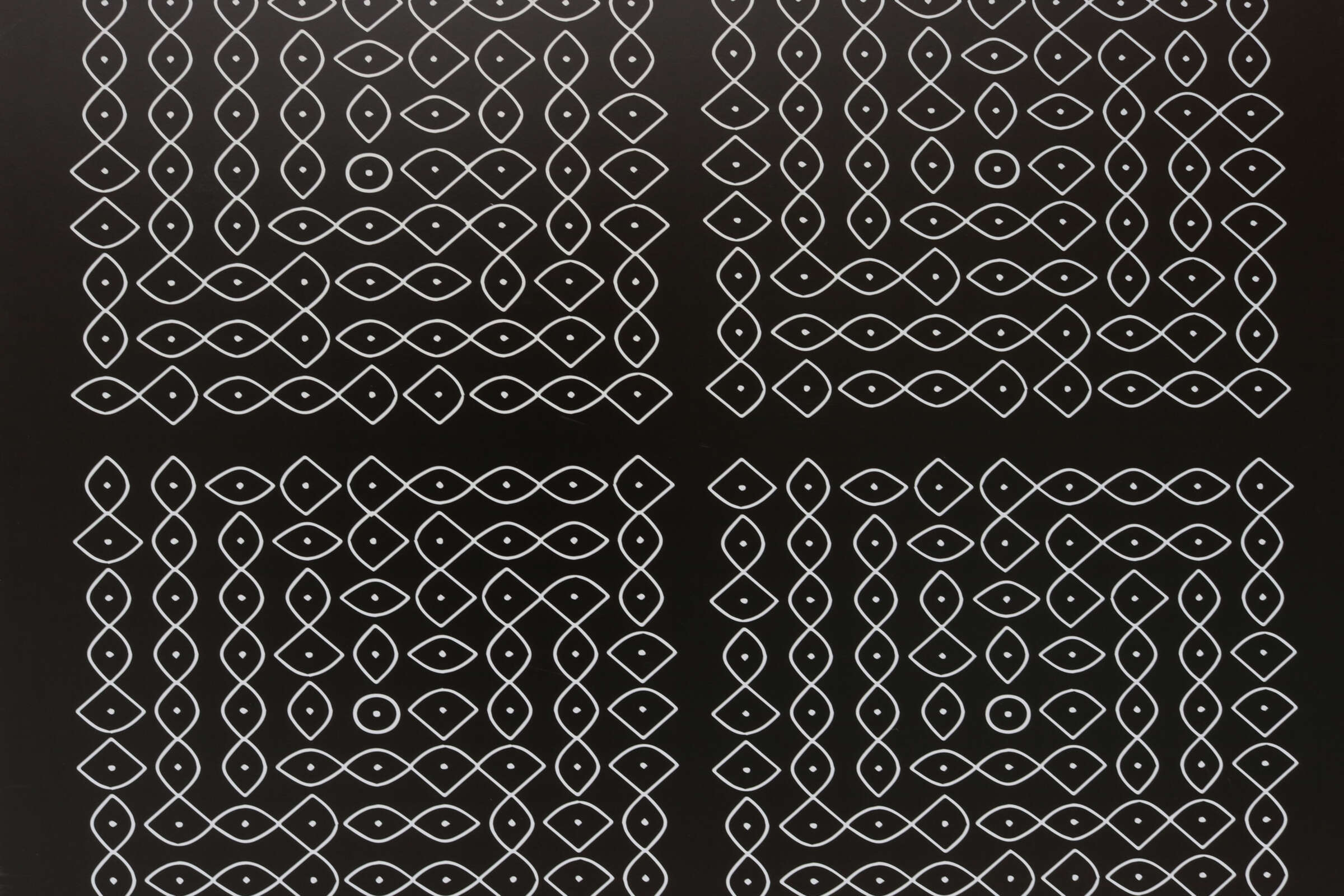 A black background with four intricate, symmetrical patterns in white. Each pattern consists of interconnected loops and eye-shaped designs, creating a complex, visually appealing geometric arrangement. The patterns are organized in a grid-like fashion.