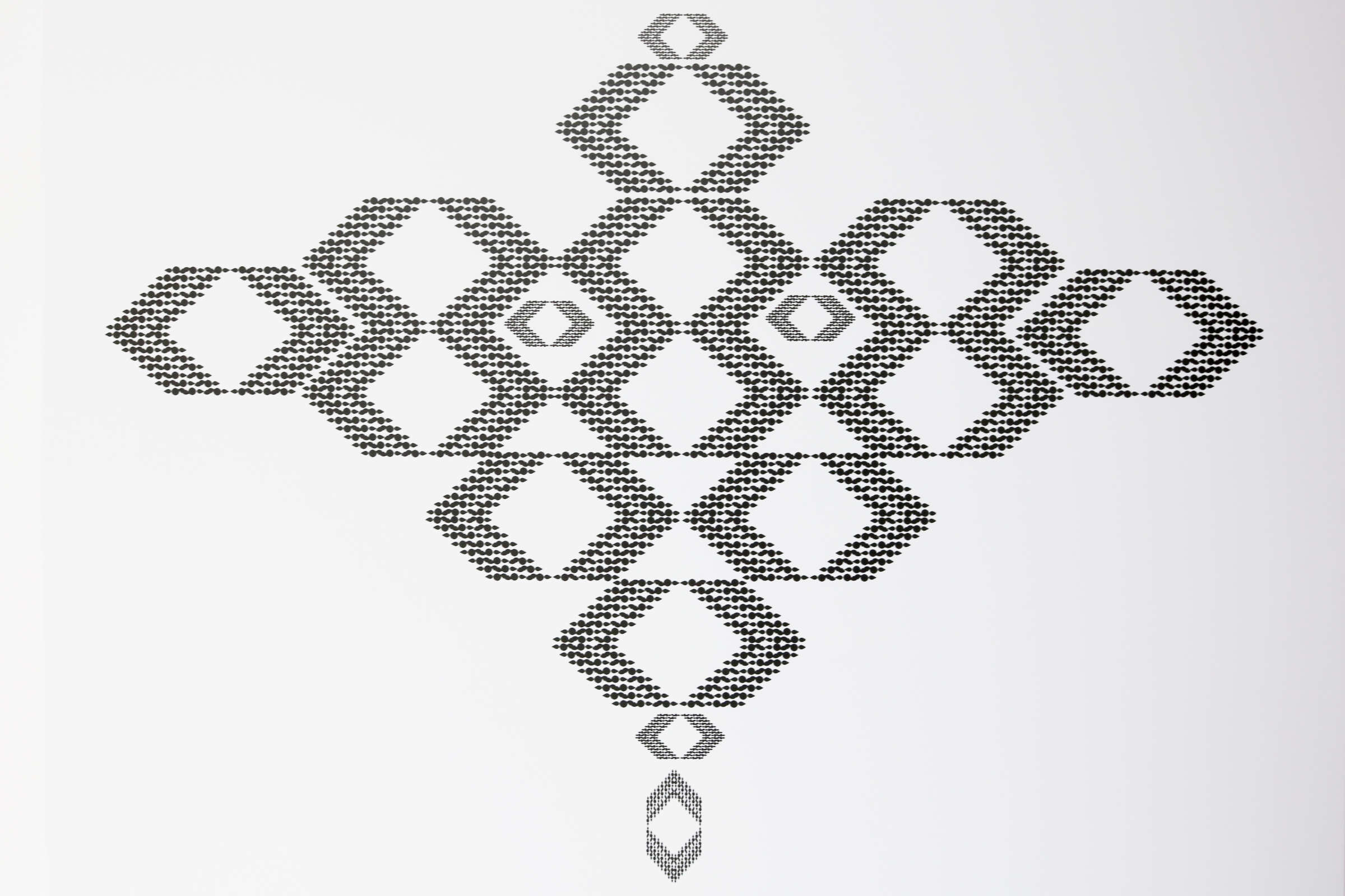 An intricate geometric pattern composed of small, repeating triangular shapes. The design forms a symmetrical arrangement of interlocking diamond shapes, displayed in a vertical orientation on a white background.