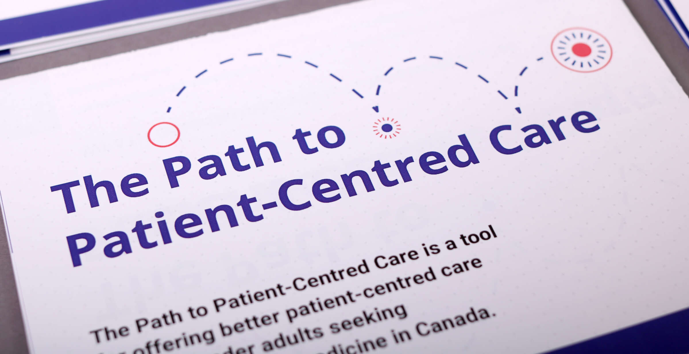 Close-up of a document titled "The Path to Patient-Centred Care". The subtitle reads, "The Path to Patient-Centred Care is a tool offering better patient-centred care for older adults seeking medicine in Canada." Blue and red graphic elements are present on the document.