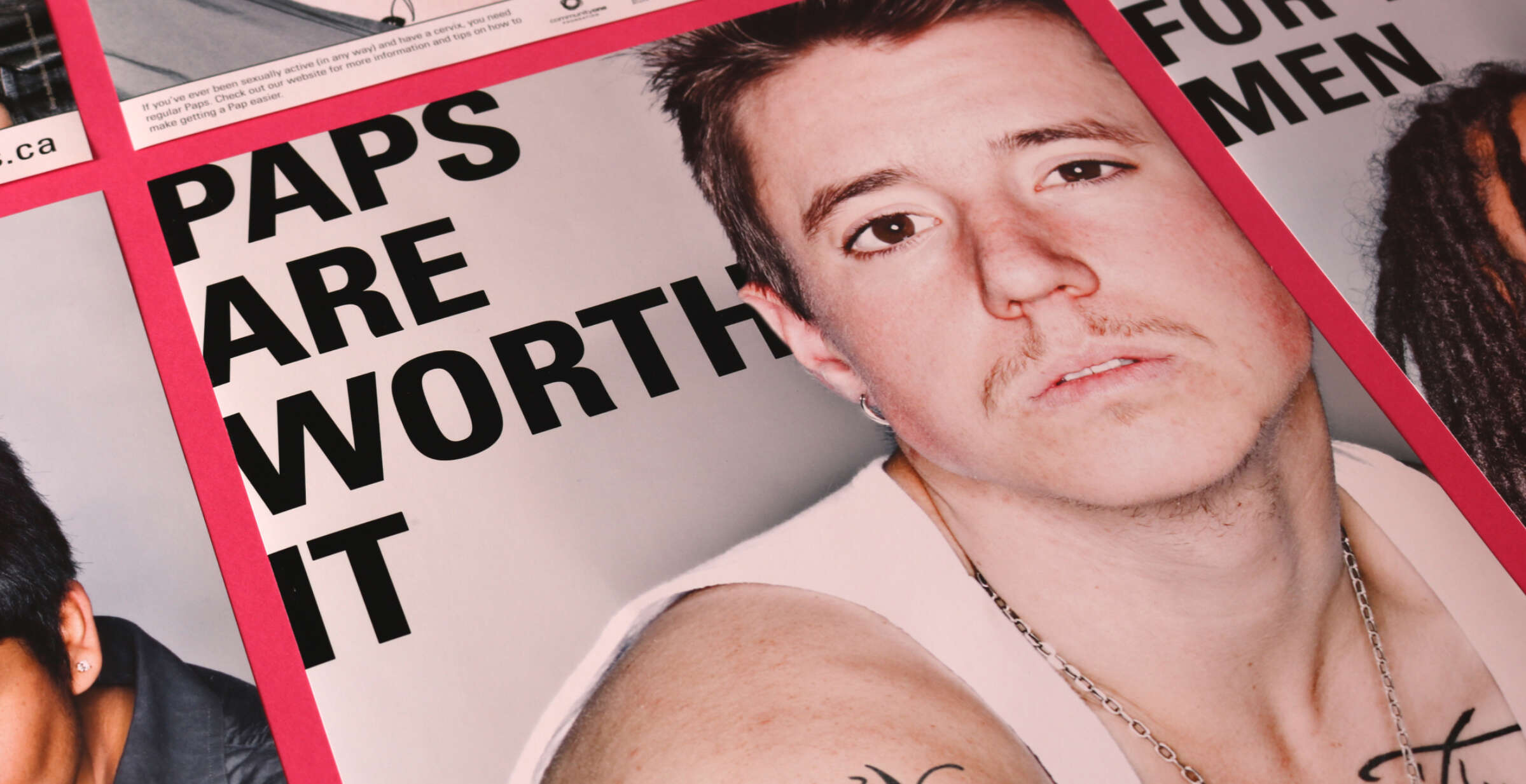 Close-up of a poster featuring a person with short hair and a mustache, wearing a white tank top and a chain necklace. The text on the poster reads, "PAPS ARE WORTH IT." Other elements of the poster are partially visible.