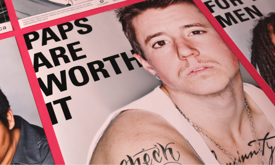 A poster features a person with short hair and a mustache, wearing a white tank top and necklace. The text reads "Paps are worth it." Tattoos are visible on the person's arm.